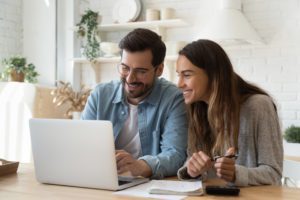 Happy young couple paying bills online in computer app | Massachusetts Association of Buyer Agents  | homebuyer real estate buyers broker