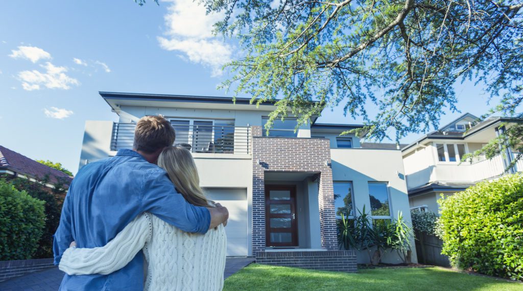 Couple standing in front of their new home | Massachusetts Association of Buyer Agents Couple standing in front of their new home