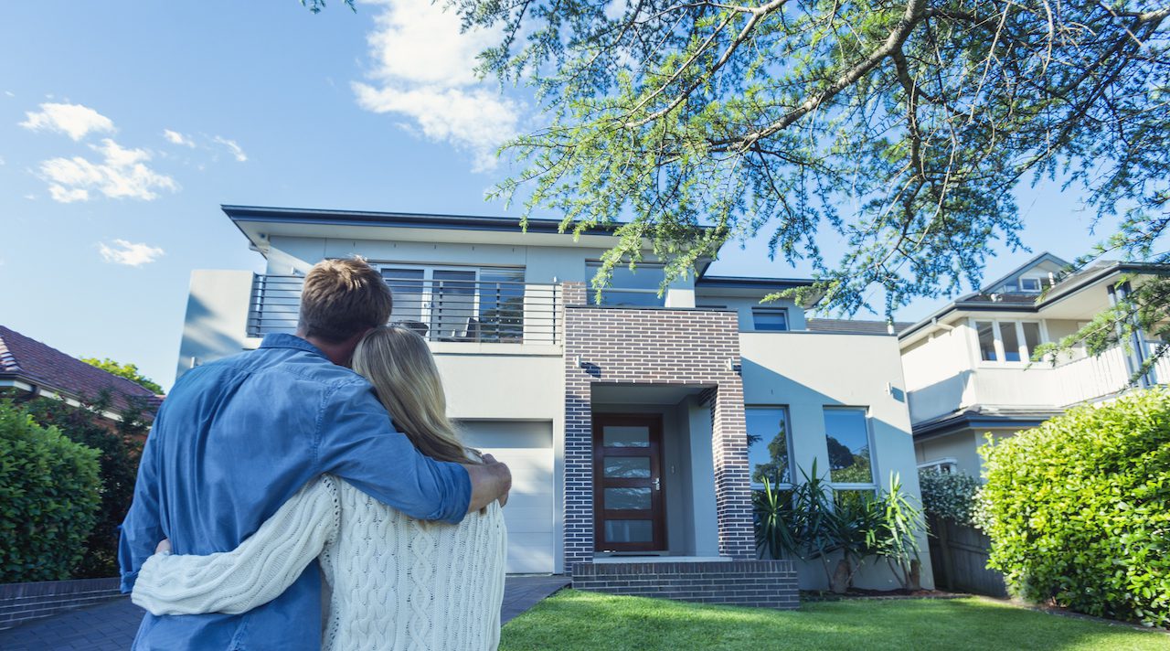 Couple standing in front of their new home.
