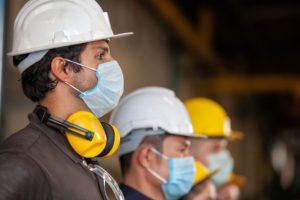 Workers wear protective face masks for safety in machine industrial factory