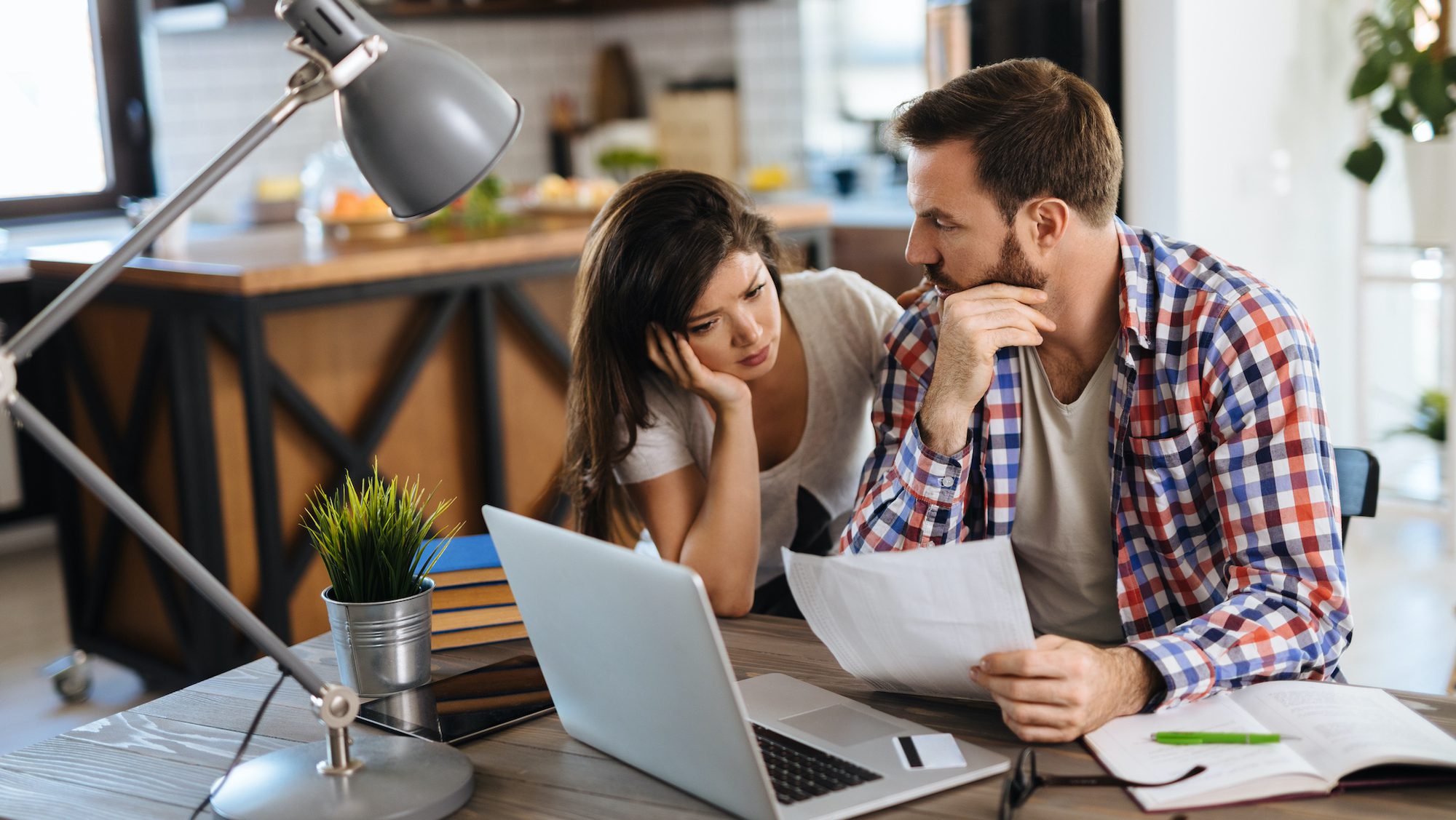 Frustrated couple checking bills at home using laptop