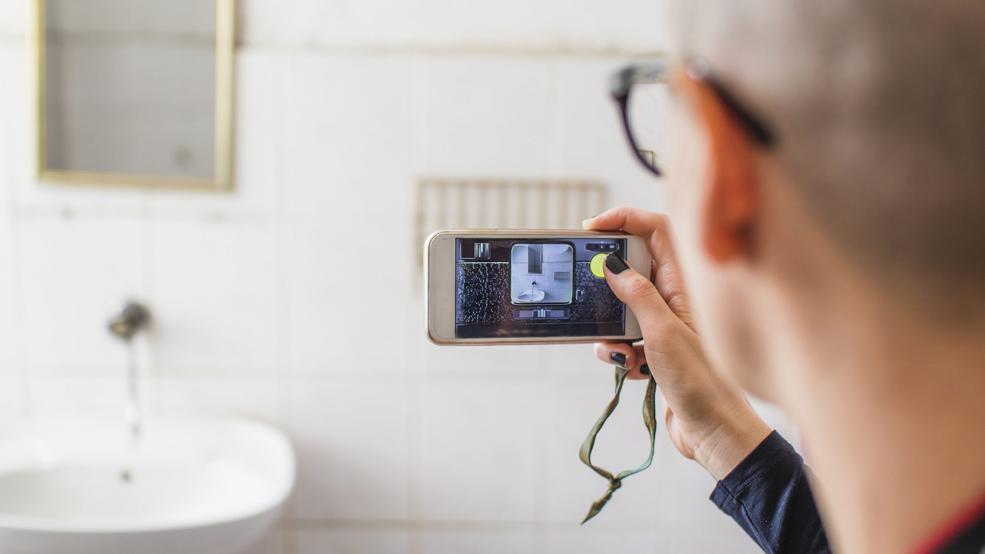 Bald young woman taking photos with her cellphone in a abandoned washroom