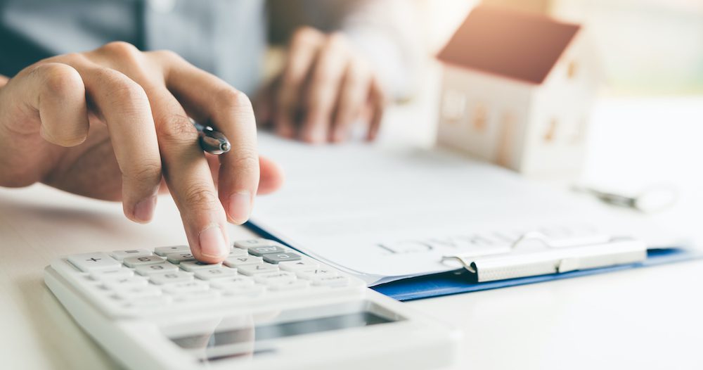 Home agents are using a calculator to calculate the loan period each month for the customer.