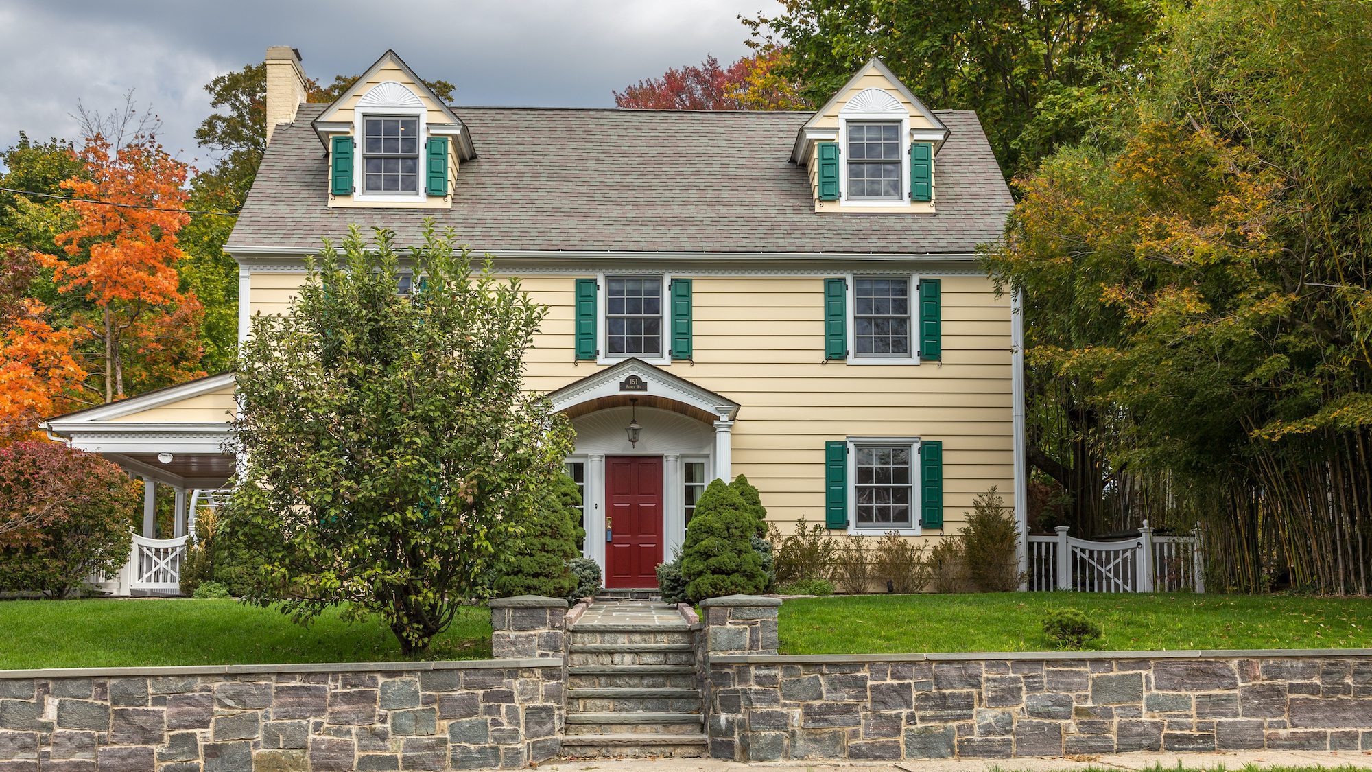 Single Family Home with Beige Clapboard Exterior and Trees in Autumn Colors (Foliage) in Sleepy Hollow, Hudson Valley, New York.